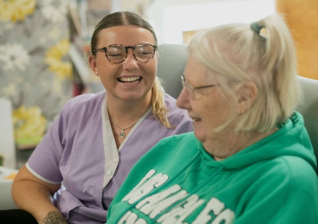 A healthcare professional providing compassionate support to an elderly patient in a care setting, demonstrating 24hr Response Care's commitment to reliable and empathetic emergency assistance.