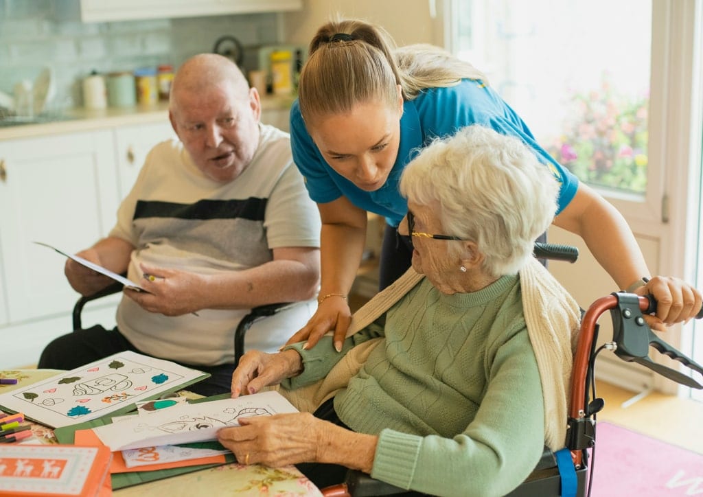 Compassionate caregiver providing support to elderly woman in a home setting, promoting home care and assistance services for seniors.