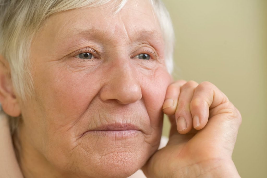 Close-up of an elderly woman with a thoughtful expression, representing urgent home care and support services for seniors needing immediate assistance.
